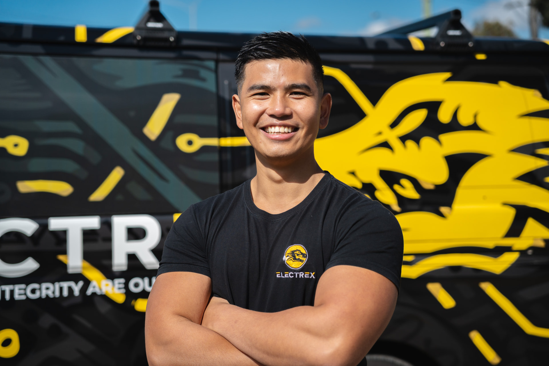 Smiling Electrex technician standing in front of a branded Electrex service van
